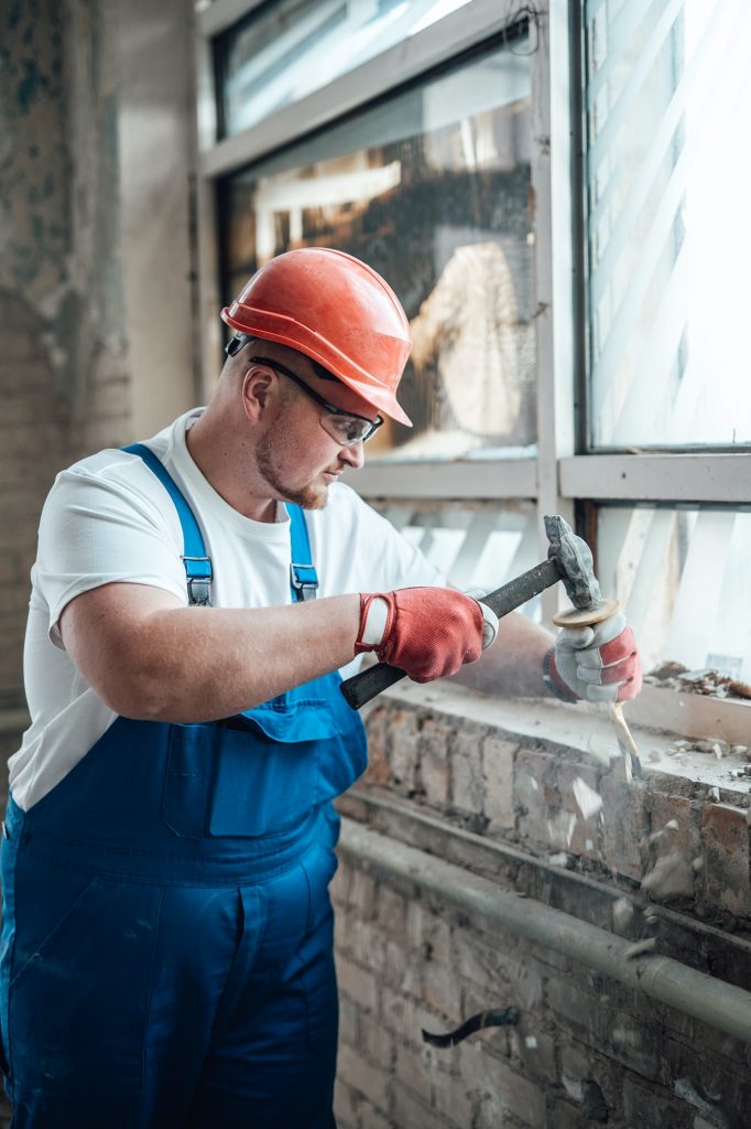 Construction worker working with a hammer, destroying old brick walls